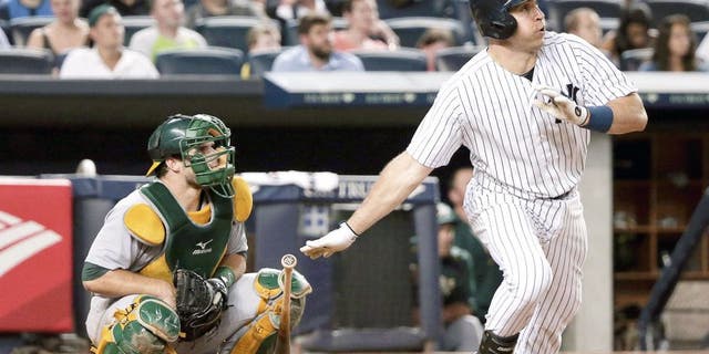 New York Yankees' Mark Teixeira, right, follows through on a solo home run as Oakland Athletics catcher Josh Phegley watches during the sixth inning of a baseball game, Wednesday, July 8, 2015, in New York. (AP Photo/Julie Jacobson)