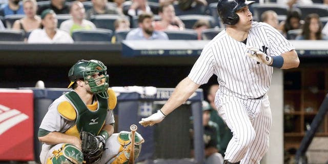 New York Yankees' Mark Teixeira, right, follows through on a solo home run as Oakland Athletics catcher Josh Phegley watches during the sixth inning of a baseball game, Wednesday, July 8, 2015, in New York. (AP Photo/Julie Jacobson)