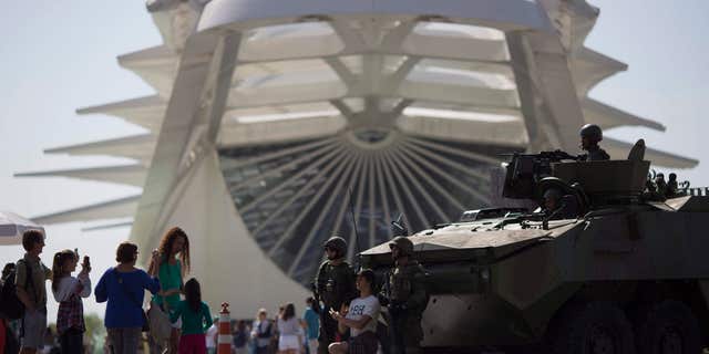 People take pictures with marines and their armored vehicle outside the Museum of Tomorrow in Rio de Janeiro, Brazil.
