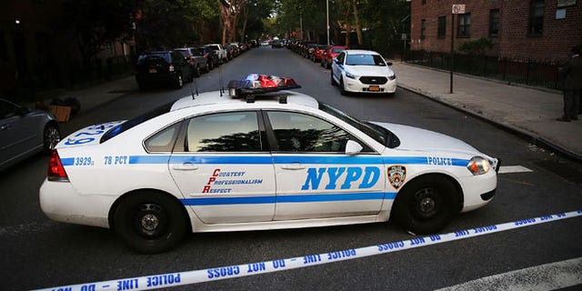A police car is parked at a crime scene where three people were shot on June 10, 2015 in Brooklyn, N.Y.