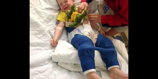 In this June 26, 2017 photo provided by Eddie Hill, Hill's son Colton is comforted while lying in a hospital bed at Johns Hopkins All Children's Hospital in St. Petersburg, Fla.