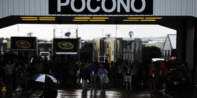 LONG POND, PA - AUGUST 05: A crew member walks through the garage area as rain delays the start of the NASCAR Sprint Cup Series Pennsylvania 400 at Pocono Raceway on August 5, 2012 in Long Pond, Pennsylvania. (Photo by Patrick Smith/Getty Images for NASCAR)