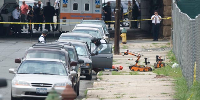 July 14: Police in protective gear look inside a car after they used robots to remove suspicious items from a car parked below a railroad overpass in Newark, N.J.