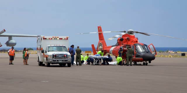 In this photo provided by the U.S. Coast Guard, Coast Guard crews safely deliver David McMahon and Sidney Uemoto to emergency medical personnel in Kona, Hawaii, Friday, July 15, 2016, following their rescue nine miles off Kona.