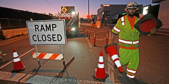 July 16: A construction worker places orange cones to close the ramp of Interstate 405 freeway at Santa Monica Boulevard in Los Angeles.
