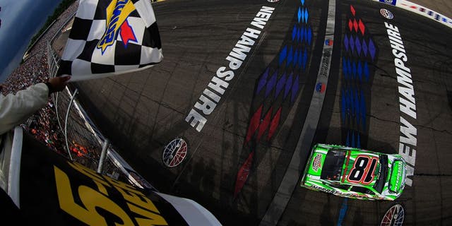 LOUDON, NH - JULY 19: Kyle Busch, driver of the #18 Interstate Batteries Toyota, takes the checkered flag to win the NASCAR Sprint Cup Series 5-Hour ENERGY 301 at New Hampshire Motor Speedway on July 19, 2015 in Loudon, New Hampshire. (Photo by Chris Trotman/NASCAR via Getty Images)