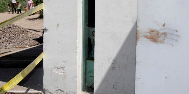 July 18: A dark red stain is seen at a wall of a site marked as a crime scene by police at the entrance of a house where a party was interrupted by gunmen early Sunday in the town of Torreon, in the Mexican northern state of Coahuila.