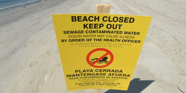 A sign is posted at Alamitos Beach warning of the dangers of sewage contaminated water Tuesday, July 19, 2016, in Long Beach, Calif.