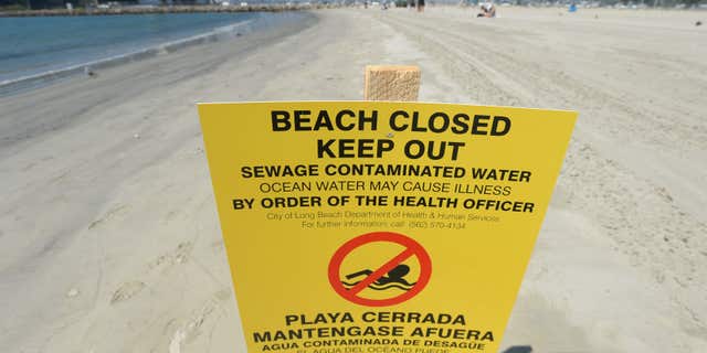 A sign is posted at Alamitos Beach warning of the dangers of sewage contaminated water Tuesday, July 19, 2016, in Long Beach, Calif.
