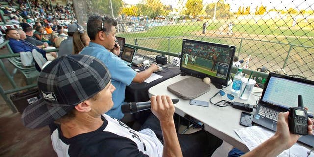 Former major league outfielder Eric Byrnes uses a computerized video system to call balls and strikes at an independent minor league baseball game between the San Rafael Pacifics and Vallejo Admirals Tuesday, July 28, 2015, in San Rafael, Calif. On Tuesday night, the computer system stood in for pitch calls in what is considered to be the first professional game without the umpire making those decisions. A full umpiring crew will be there for everything else. (AP Photo/Eric Risberg)