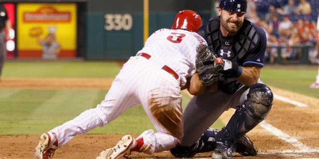 Tampa Bay Rays catcher Curt Casali, right, takes the hit from Philadelphia Phillies' Jeff Francoeur, left, as Francoeur is out at home during the fifth inning of a baseball game, Monday, July 20, 2015, in Philadelphia. (AP Photo/Chris Szagola)