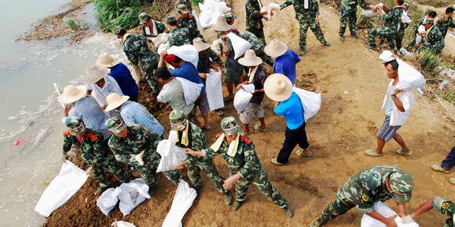 In this Tuesday, July 20, 2010 photo, paramilitary police and workers move sandbags to fortify the Fanghu dyke in Pengze county, in central China's Jiangxi province. Flooding this year has killed 701 people, left 347 missing and caused tens of billions of dollars in damage, the worst toll across the board that China has seen in a decade, a senior Chinese official said Wednesday. (AP Photo) ** CHINA OUT **