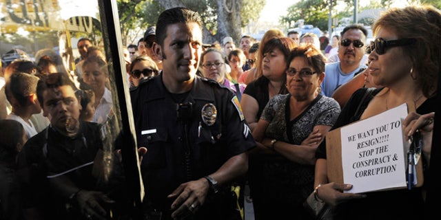 July 22: A Bell police officer patrols outside a special city council meeting to consider the firing of top officials in Bell, Calif.