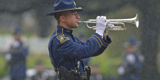 July 25, 2016: A member of the Louisiana State Police Honor Guard plays "Taps" through driving rain during funeral services for Baton Rouge police Cpl. Montrell Jackson in Baton Rouge, La.