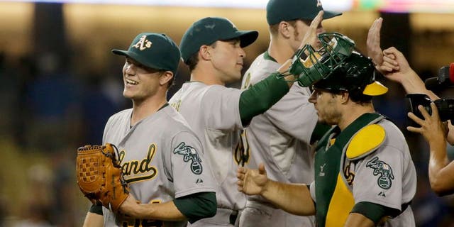 Oakland Athletics starting pitcher Sonny Gray, left, celebrates with teammates after they shutout the Los Angeles Dodgers 2-0 in a baseball game, Tuesday, July 28, 2015, in Los Angeles. (AP Photo/Chris Carlson)