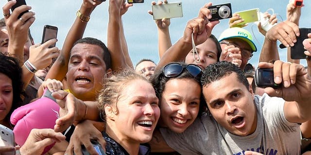 RIO DE JANEIRO, BRAZIL - JULY 29: Womens bantamweight champion Ronda Rousey of the United States takes photos with fans during open training session at Pepe Beach on July 29, 2015 in Rio de Janeiro, Brazil. (Photo by Buda Mendes/Zuffa LLC/Zuffa LLC via Getty Images)