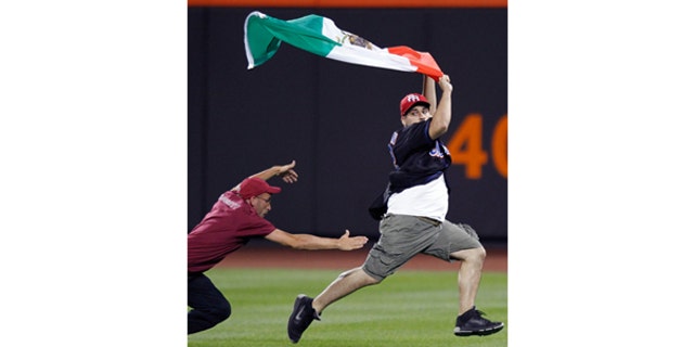 July 30: A Citi Field security guard tries to tackle a young man carrying a Mexican flag who ran onto the field in the seventh inning of the New York Mets vs the Arizona Diamondbacks baseball game in New York.