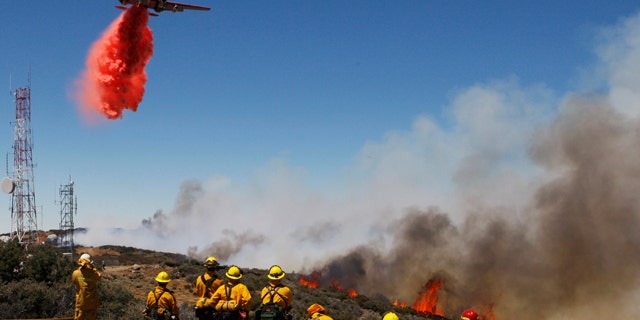 A tanker drop fire retardant the crest of the Hauser Peak in Palmdale, Calif, on Friday, July 30, 2010. Aircraft and hundreds of firefighters are concentrating on protecting the densely populated Palmdale area a few miles away and a cluster of power transmission lines that provide electricity to much of Southern California. (AP Photo/Damian Dovarganes)