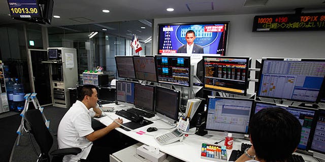 Aug. 1: Employees of a foreign exchange firm monitor screens, with a television news reports that President Obama announced U.S. debt limit deal, in Tokyo.