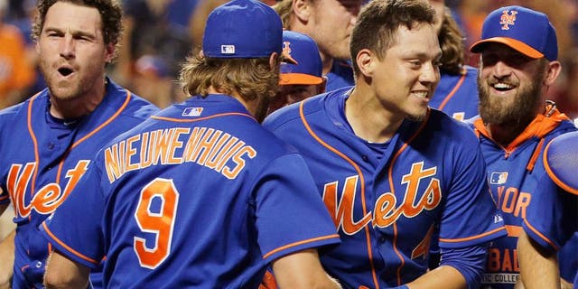 New York Mets' Wilmer Flores, center right, is mobbed by teammates after hitting a walkoff solo home run during the twelfth inning of a baseball game to defeat the Washington Nationals 2-1, Friday, July 31, 2015, in New York. (AP Photo/Julie Jacobson)