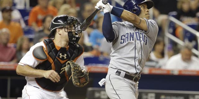 San Diego Padres' Alexi Amarista, right, follows through on a sacrifice fly to score Derek Norris in the fourth inning of a baseball game against the Miami Marlins, Friday, July 31, 2015, in Miami. At left is Miami Marlins catcher J.T. Realmuto. (AP Photo/Lynne Sladky)