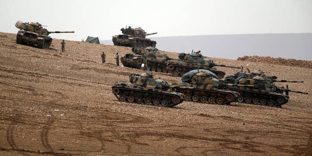 Turkish soldiers hold their positions with their tanks on a hilltop on the outskirts of Suruc, at the Turkey-Syria border, overlooking Kobani, Syria, during fighting between Syrian Kurds and the militants of Islamic State group, Sunday, Oct. 12, 2014. Kobani, also known as Ayn Arab, and its surrounding areas, has been under assault by extremists of the Islamic State group since mid-September and is being defended by Kurdish fighters.(AP Photo/Lefteris Pitarakis)