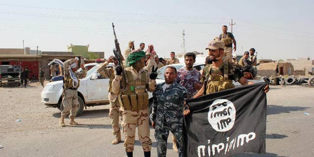 In this Monday, Sept. 1, 2014 photo, Shiite militiamen hold the flag of the Islamic State group they captured, during an operation outside Amirli, some 105 miles (170 kilometers) north of Baghdad, Iraq. Under the shadow of the Islamic State group threat, governments from France to Indonesia are moving aggressively to block would-be jihadis from taking their fight to Syria and Iraq. New laws make it easier to seize passports. Suspected fighters are being plucked from planes. Authorities are blocking finances and shutting down radical mosques. Behind the scenes, Western intelligence agencies are striving to stay ahead of tech-savvy radicalized Muslims by pressuring Silicon Valley firms to wipe extremist content from websites and toying with new technologies to identify returning fighters at the border. Britain has taken a particularly active role in censoring content deemed to break the country’s strict rules against extremist propaganda. U.K. officials recently revealed it had been granted “super flagger” status on sites such as YouTube, meaning their requests to remove videos with grisly content or that encourage terrorism are fast-tracked. (AP Photo)