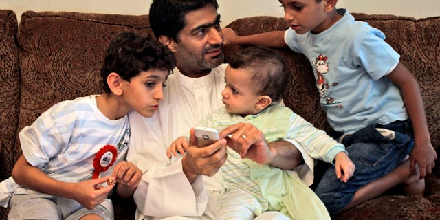 FILE - In this Tuesday, Nov. 29, 2011 file photo, Ahmed Mansour, an Emirati blogger and a human rights activists talks with his children after he was pardoned by UAE's president and released from jail in Dubai, United Arab Emirates. In early March 2013, a total of 94 people were put on trial on charges of seeking to overthrow the UAE government and holding ties to the Muslim Brotherhood and other groups. The defendants pleaded not guilty and complained of abuses after their arrests. Mansour and four others including a former legal adviser to the UAE's armed forces were among the first to face arrests for alleged anti-state crimes in early 2011 after signing an online petition urging for political reforms, including free elections for parliament. (AP Photo/Kamran Jebreili, File)