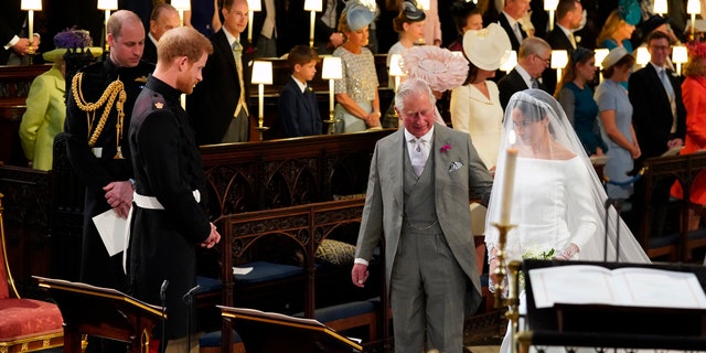 Britain's Prince Harry looks at his bride, Meghan Markle, as she arrives accompanied by Prince Charles during the wedding ceremony of Prince Harry and Meghan Markle at St. George's Chapel in Windsor Castle in Windsor, near London, England, Saturday, May 19, 2018.