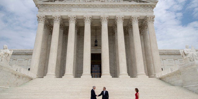 New Associate Supreme Court Justice Neil Gorsuch, left, shakes hands with Chief Justice John Roberts, as Gorsuch's wife Louise arrives at right, at the Supreme Court in Washington, Thursday, June 15, 2017, following Gorsuch investiture ceremony to mark his ascension to the bench. (AP Photo/J. Scott Applewhite)