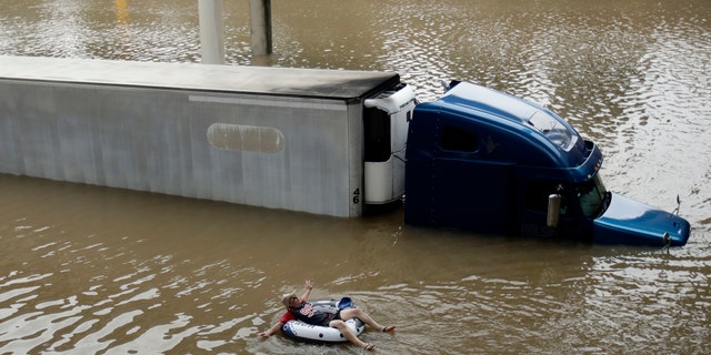After helping the driver of the submerged truck get to safety, a man floats on the freeway flooded by Tropical Storm Harvey on Sunday, Aug. 27, 2017, near downtown Houston. (