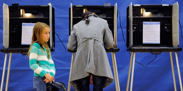 Nov. 4, 2014: Alice Kunde, 8, left, waits for her mother Laura Kunde to vote at the Barnum Recreation Center in Denver.