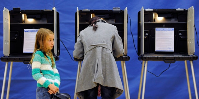 Nov. 4, 2014: Alice Kunde, 8, left, waits for her mother Laura Kunde to vote at the Barnum Recreation Center in Denver.