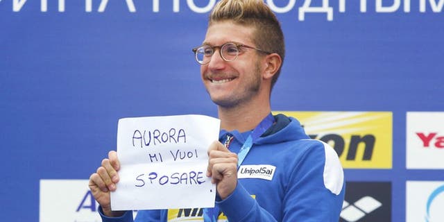 Italy's gold medal winner Simone Ruffini shows a placard "Aurora, you want to marry me" during the ceremony for the men's 25km open water swim competition at the Swimming World Championships in Kazan, Russia, Saturday, Aug. 1, 2015. (AP Photo/Sergei Grits)