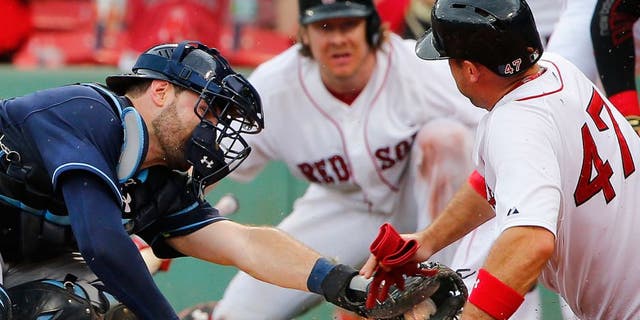 Boston Red Sox's Travis Shaw slides safely into home around the tag of Tampa Bay Rays catcher Curt Casali during the sixth inning of a baseball game at Fenway Park in Boston Saturday, Aug. 1, 2015. (AP Photo/Winslow Townson)