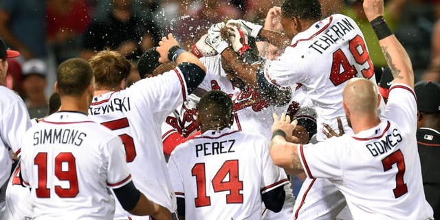Aug 3, 2015; Atlanta, GA, USA; Atlanta Braves third baseman Adonis Garcia (center) is mobbed by teammates after hitting a game winning two run home run against the San Francisco Giants during the twelfth inning at Turner Field. The Braves defeated the Giants 9-8 in 12 innings. Mandatory Credit: Dale Zanine-USA TODAY Sports