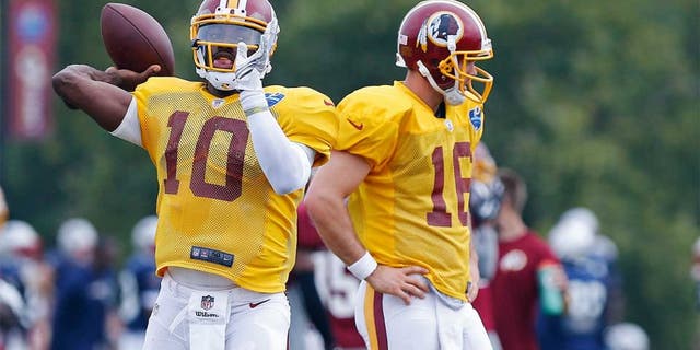 Aug 4, 2014; Richmond, VA, USA; Washington Redskins quarterback Robert Griffin III (10) throws the ball as Redskins quarterback Colt McCoy (16) looks on during joint practice with the New England Patriots on day ten of training camp at the Bon Secours Washington Redskins Training Center. Mandatory Credit: Geoff Burke-USA TODAY Sports