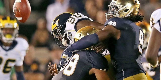 SOUTH BEND, IN - SEPTEMBER 06: Devin Gardner #98 of the Michigan Wolverines fumbles the ball as he is hit by Joe Schmidt #38 (L) abd Jaylon Smith #9 of the Notre Dame Fighting Irish at Notre Dame Stadium on September 6, 2014 in South Bend, Indiana. (Photo by Jonathan Daniel/Getty Images)