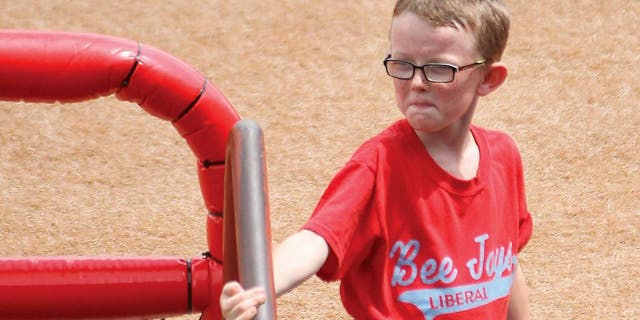In this Aug. 1, 2015, photo, bat boy Kaiser Carlile, 9, gets ready for a National Baseball Congress World Series baseball game between the Liberal Bee Jays and San?Diego Waves outside the dugout in Wichita, Kan. Kaiser, who was wearing a helmet, was accidentally hit in the head during the game by a follow-through swing near the on-deck circle. He died on Sunday. (Earl Watt/Leader & Times via AP) MANDATORY CREDIT