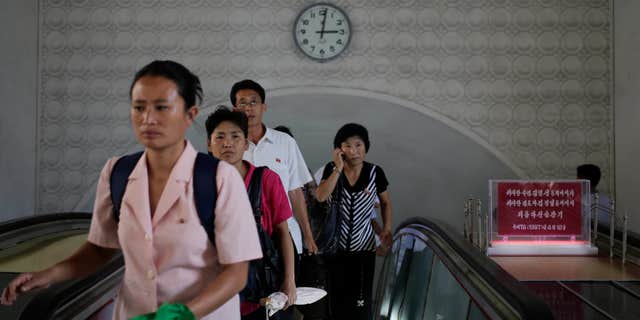 Sept. 1, 2014: A clock hangs on the wall as North Koreans leave an underground train station in Pyongyang, North Korea.
