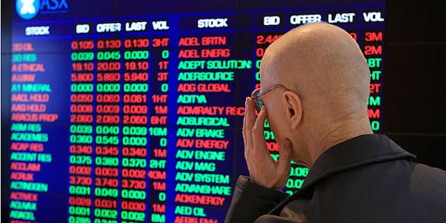 Aug. 8: Rudolf Oultz watches the display board at the Australia Stock Exchange in Sydney. Australian and New Zealand markets opened lower in reaction to ratings agency Standard and Poor's downgrading of the United States government credit rating from AAA to AA+.