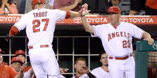 Aug 7, 2015; Anaheim, CA, USA; Los Angeles Angels pitching coach Mike Butcher (23) congratulates Los Angeles Angels center fielder Mike Trout (27) for scoring against the Baltimore Orioles during the fourth inning at Angel Stadium of Anaheim. Mandatory Credit: Richard Mackson-USA TODAY Sports