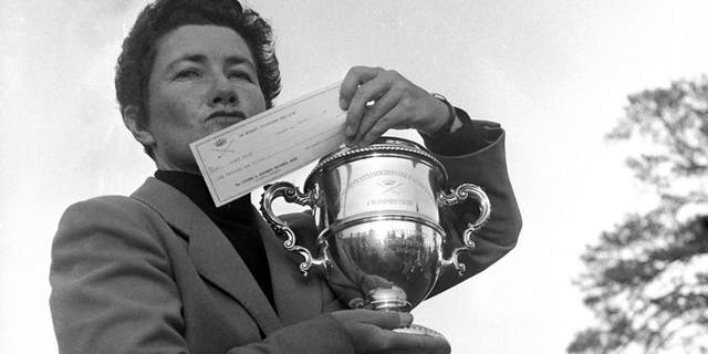 FILE - In this March 15, 1959 file photo, Louise Suggs of Atlanta, Ga., holds up the winner's cup and a check for $1,000 after winning the Women's Titleholders golf championship in Augusta, Ga. The LPGA Tour says Suggs, an LPGA founder and one of the greatest female golfers of all time, died Friday, Aug. 7, 2015, in Sarasota, Fla. She was 91. The LPGA did not list a cause of death. (AP Photo/Horace Cort, File)