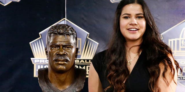 Sydney Seau, aughter of former NFL player Junior Seau, poses with a bust of her father during inductions at the Pro Football Hall of Fame Saturday, Aug. 8, 2015, in Canton, Ohio. (AP Photo/Gene J. Puskar)
