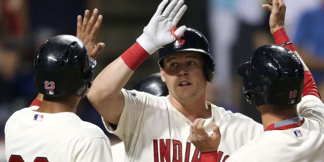 Cleveland Indians' Jerry Sands, center, is congratulated from teammates Michael Brantley, left, and Yan Gomes after hitting a grand slam off Minnesota Twins relief pitcher Blaine Boyer during the fifth inning of a baseball game, Saturday, Aug. 8, 2015, in Cleveland.