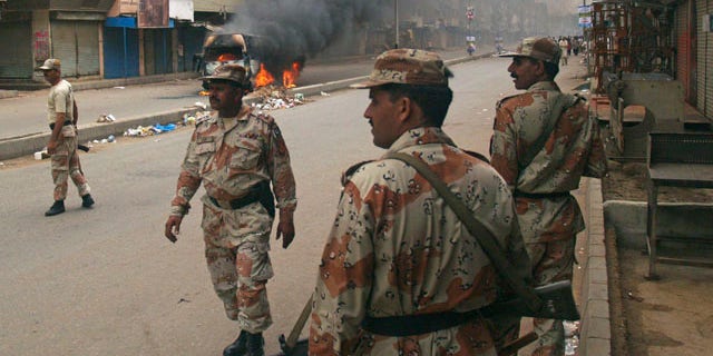 Aug. 3: Pakistani para military troops gather near a vehicle set on fire by an angry mob following the killing of a local leader of the Muttahida Quami Movement in Pakistan.