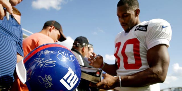 New York Giants wide receiver Victor Cruz, right, signs autographs after the Giants' joint NFL football training camp with the Cincinnati Bengals, Tuesday, Aug. 11, 2015, in Cincinnati. (AP Photo/John Minchillo)