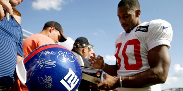 New York Giants wide receiver Victor Cruz, right, signs autographs after the Giants' joint NFL football training camp with the Cincinnati Bengals, Tuesday, Aug. 11, 2015, in Cincinnati. (AP Photo/John Minchillo)