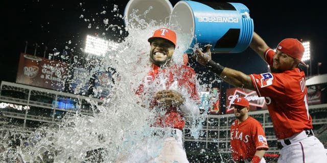Texas Rangers Delino DeShields, left, gets doused with the drink cooler by teammate Rougned Odor after a baseball game against the Tampa Bay Rays in Arlington, Texas, Friday, Aug. 14, 2015. The Rangers won 5-3. (AP Photo/LM Otero)