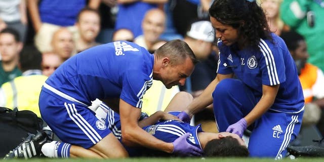 Chelsea doctor (R) Eva Carneiro and head physio Jon Fearn (L) treat Chelsea's Belgian midfielder Eden Hazard late on during the English Premier League football match between Chelsea and Swansea City at Stamford Bridge in London on August 8, 2015. Chelsea have sidelined team doctor Eva Carneiro from match-day duties after she fell foul of manager Jose Mourinho, according to British media reports on August 11, 2015. Mourinho criticised Carneiro after she ran on the pitch to treat Eden Hazard in stoppage time of Chelsea's 2-2 draw at home to Swansea City on August 8, saying she did not "understand the game". AFP PHOTO / IAN KINGTON RESTRICTED TO EDITORIAL USE. No use with unauthorized audio, video, data, fixture lists, club/league logos or 'live' services. Online in-match use limited to 75 images, no video emulation. No use in betting, games or single club/league/player publications. (Photo credit should read IAN KINGTON/AFP/Getty Images)